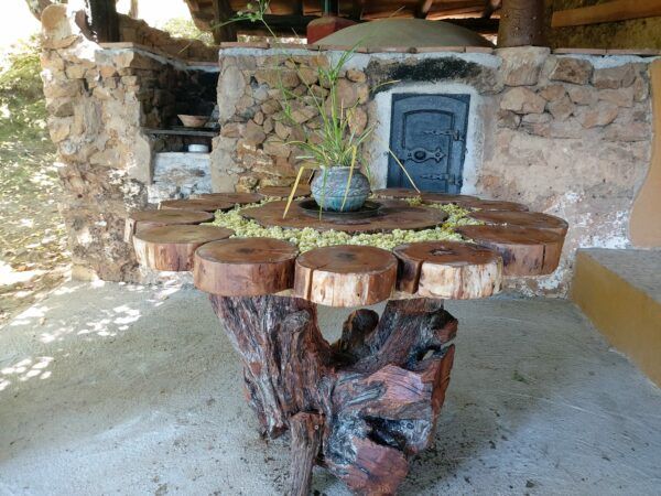 mesa hecha con troncos de árbol y horno de leña en el pagano alojamiento retiros yoga en Ávila
