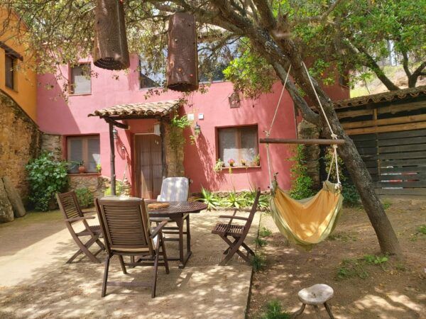 patio con mesa sillas y una hamaca en el pagano alojamiento retiros yoga en Ávila